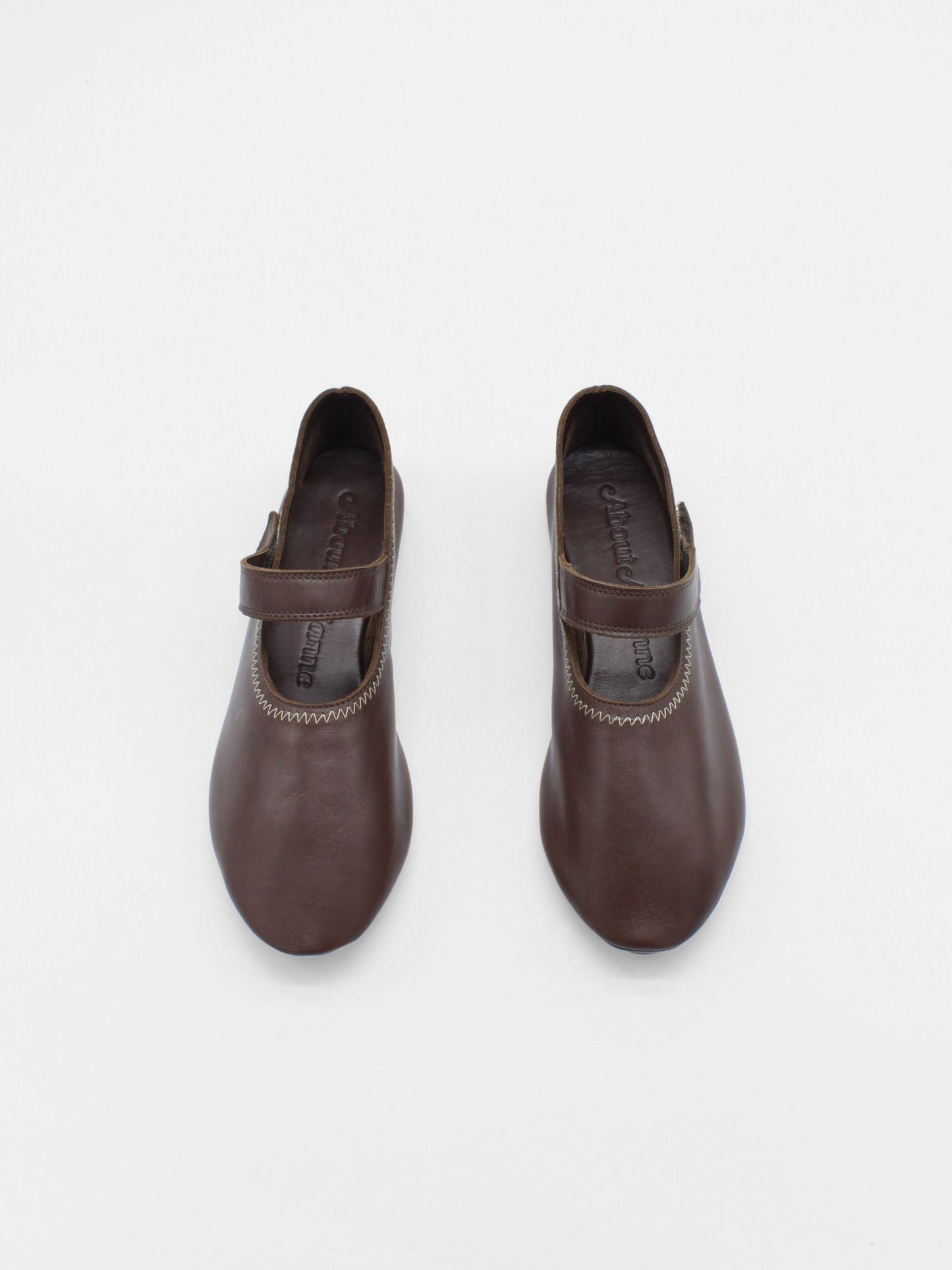 Unlined flat mary-jane made of dark brown lamb nappa leather with a shiny finish and stitching details.