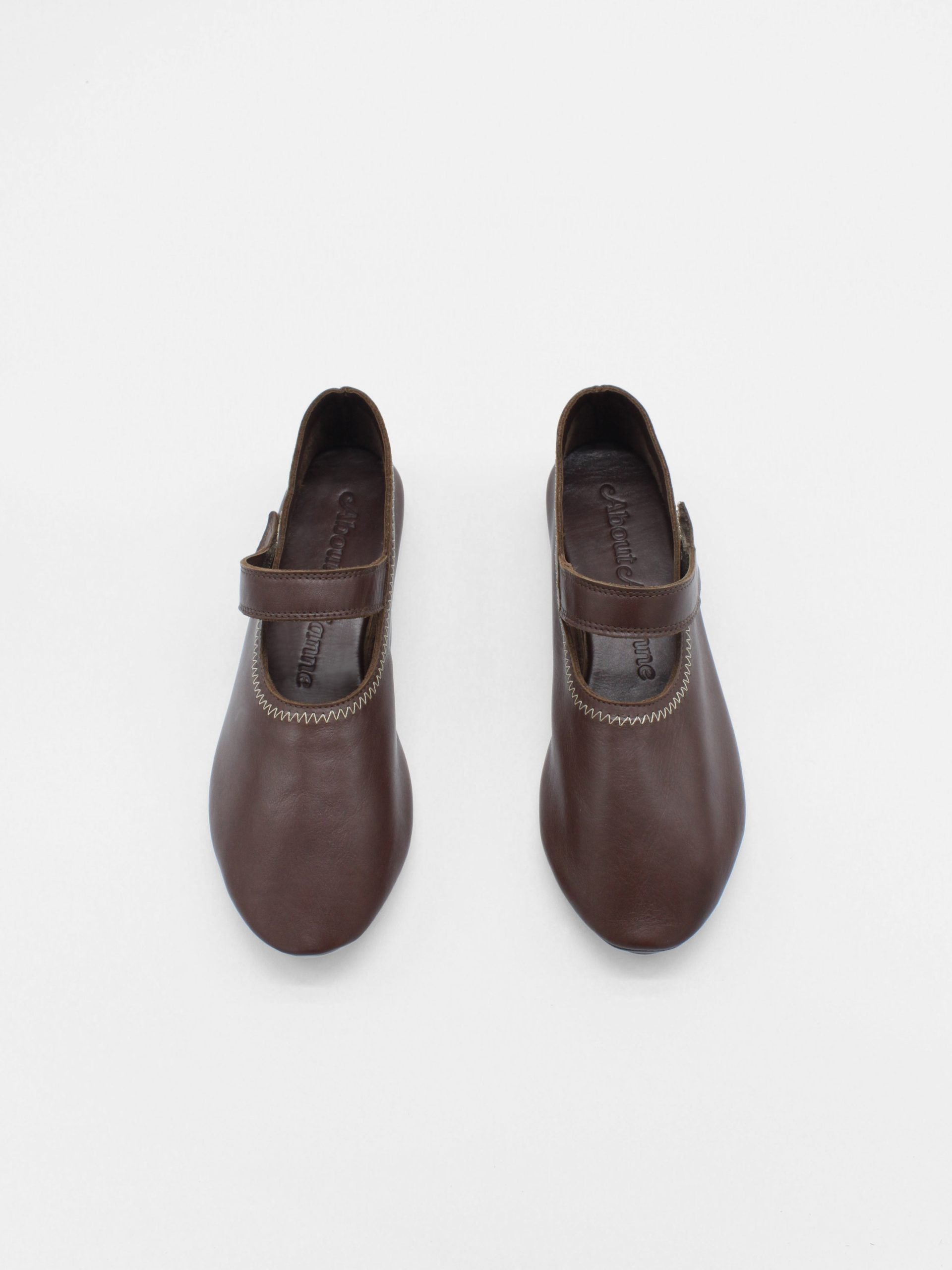 Unlined flat mary-jane made of dark brown lamb nappa leather with a shiny finish and stitching details.