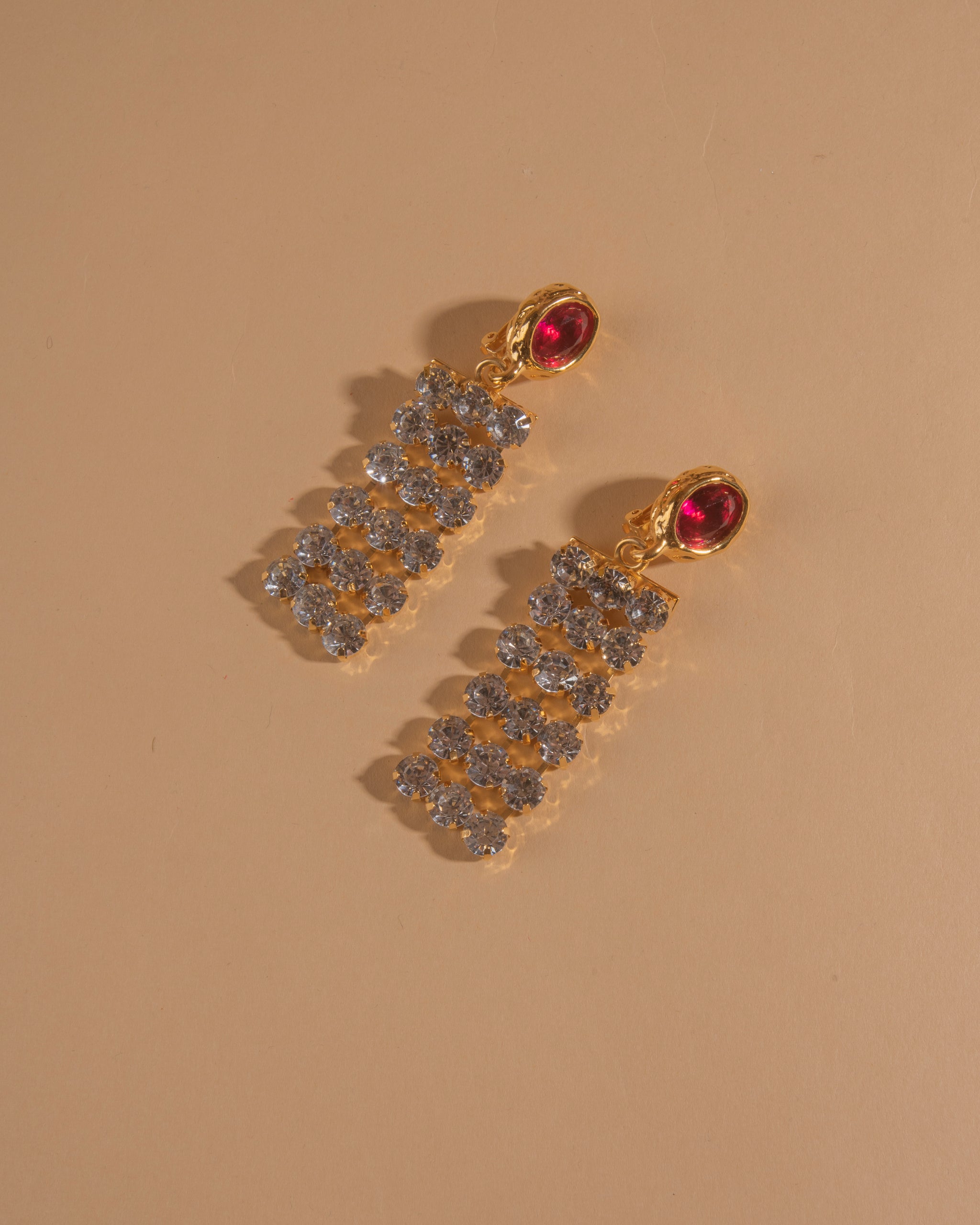 Pair of 18k gold plated clip-on earrings with glass crystal center stone and crystal chain.