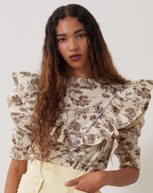 brown Toile de Jouy with bold lilac piping and matching grosgrain ribbon to really make it pop. The leg-o-mutton puff sleeves are lined with tulle for maximum volume. 100% Cotton. Slips on over head and ties in a bow at the back neck