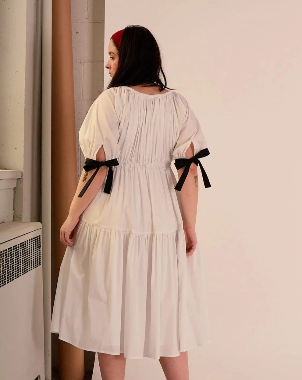 Overall white dress with extra puffy sleeves, gathered tiers, and black bow-tie details, the Jolen dress is both elegant and incredibly comfortable too. It's fully lined with cotton, slips on easily over head, and has pockets.