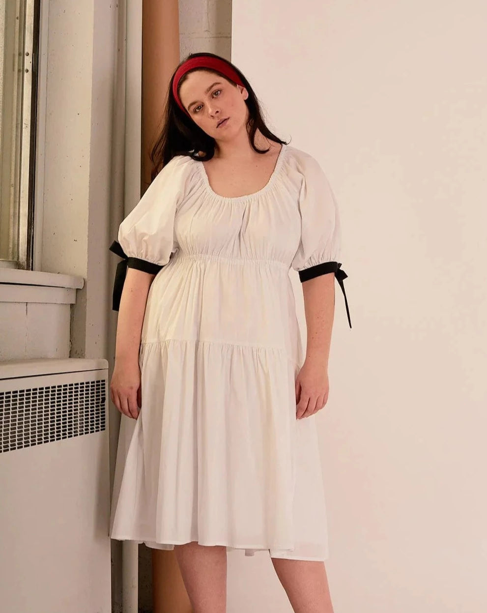 Overall white dress with extra puffy sleeves, gathered tiers, and black bow-tie details, the Jolen dress is both elegant and incredibly comfortable too. It's fully lined with cotton, slips on easily over head, and has pockets.
