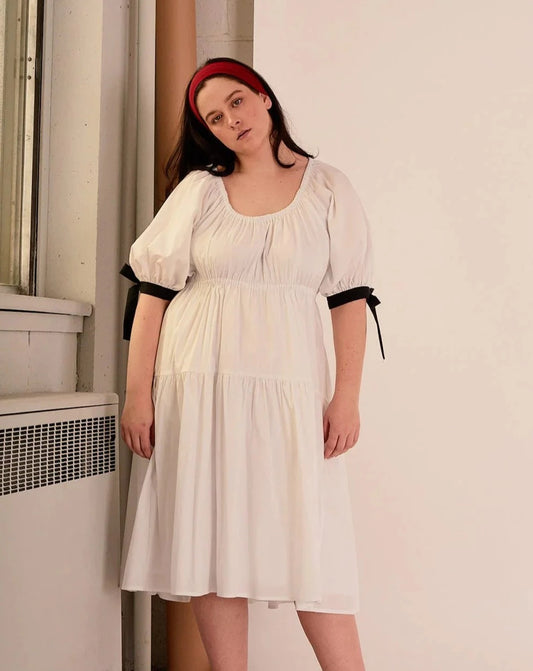 Overall white dress with extra puffy sleeves, gathered tiers, and black bow-tie details, the Jolen dress is both elegant and incredibly comfortable too. It's fully lined with cotton, slips on easily over head, and has pockets.