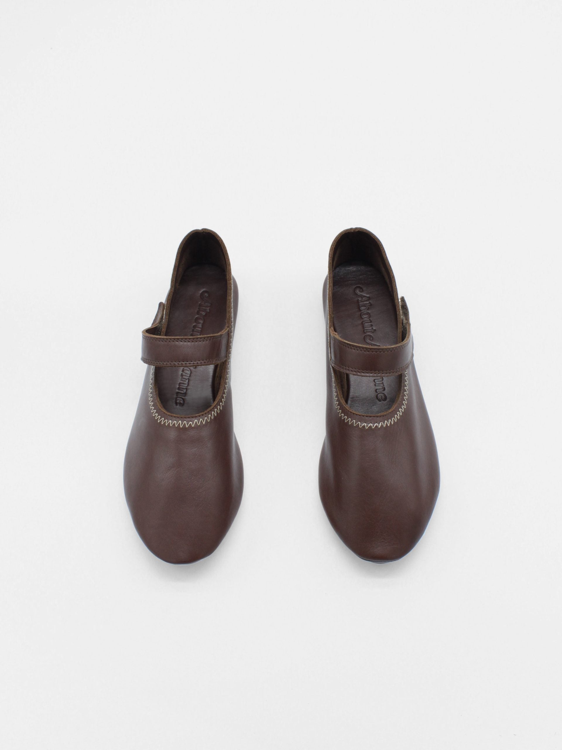 Unlined flat mary-jane made of dark brown lamb nappa leather with a shiny finish and stitching details. 