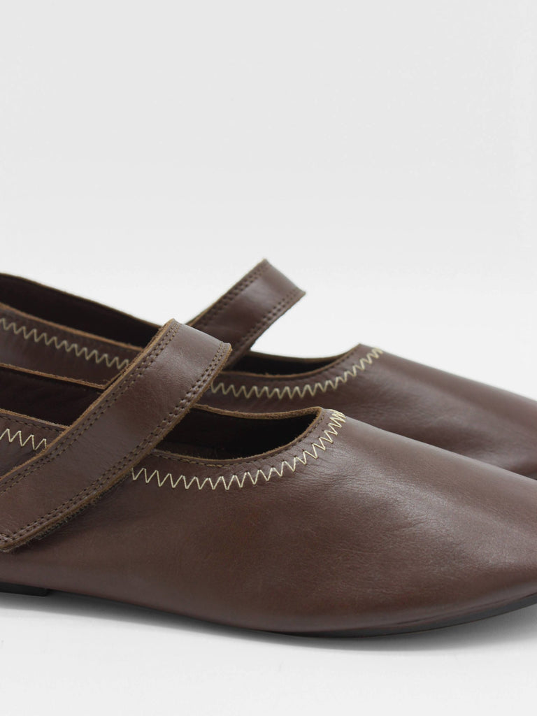 Unlined flat mary-jane made of dark brown lamb nappa leather with a shiny finish and stitching details. 