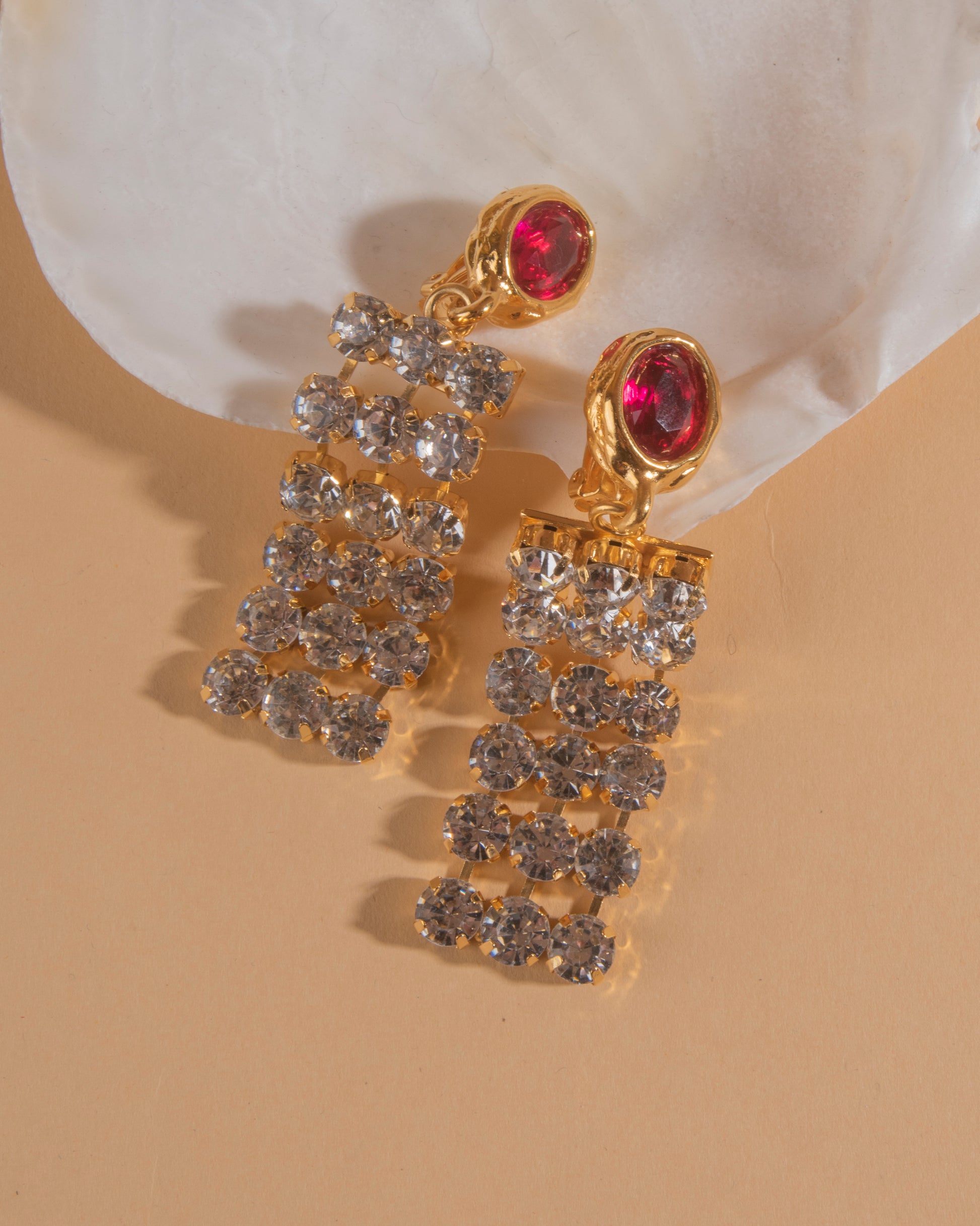 Pair of 18k gold plated clip-on earrings with glass crystal center stone and crystal chain.