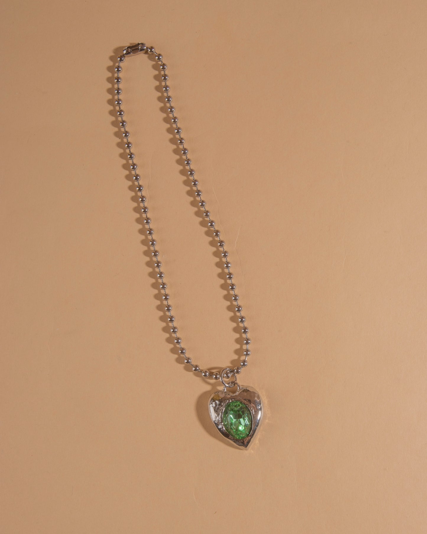 Silver-tone heart necklace set with clear glass stone on ball chain.