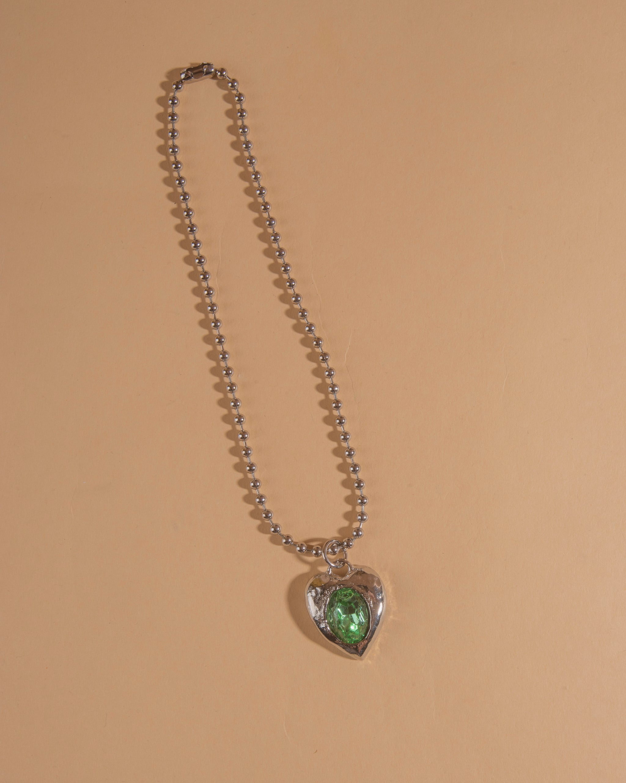 Silver-tone heart necklace set with clear glass stone on ball chain.