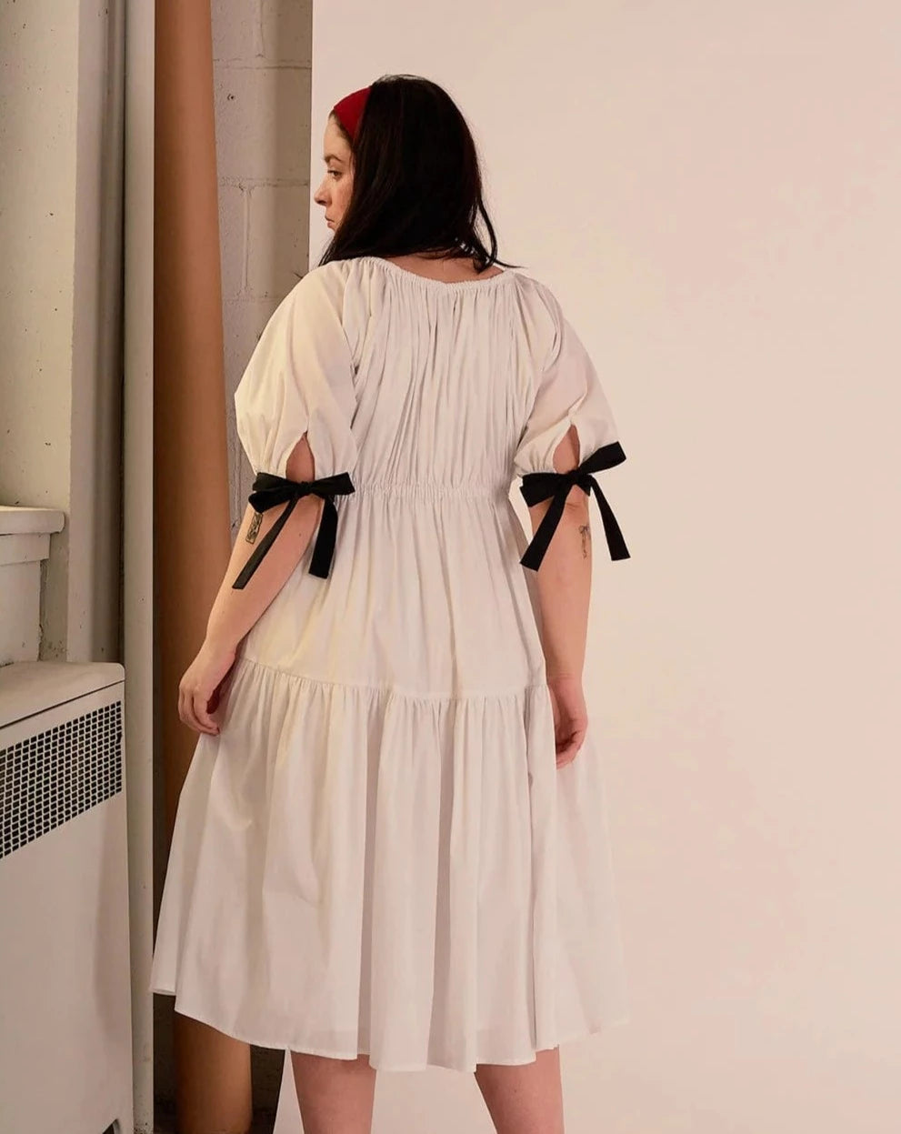 Overall white dress with extra puffy sleeves, gathered tiers, and black bow-tie details, the Jolen dress is both elegant and incredibly comfortable too. It's fully lined with cotton, slips on easily over head, and has pockets. 