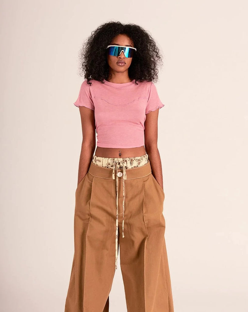 This cropped pink coloured tee is made out of a super soft blend of tencel and wool, but is still lightweight enough to wear during warm weather. The best parts are the exposed lilac coloured stitching and the super sweet ruffles on the hem and sleeves. It has a cropped fit that sits just above high-waisted jeans.