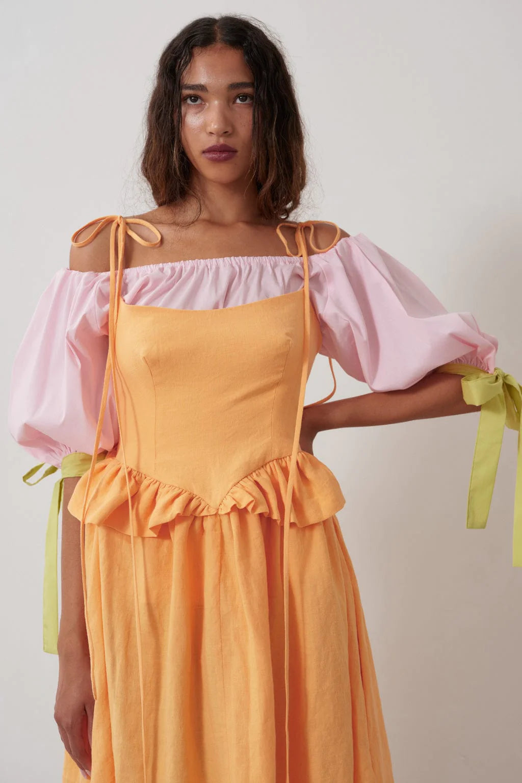 The sally top is pink with full puff sleeves that sit above the elbow with the help of big, bold adjustable green ties and an elasticized neckline so you can wear it on or off the shoulder. 