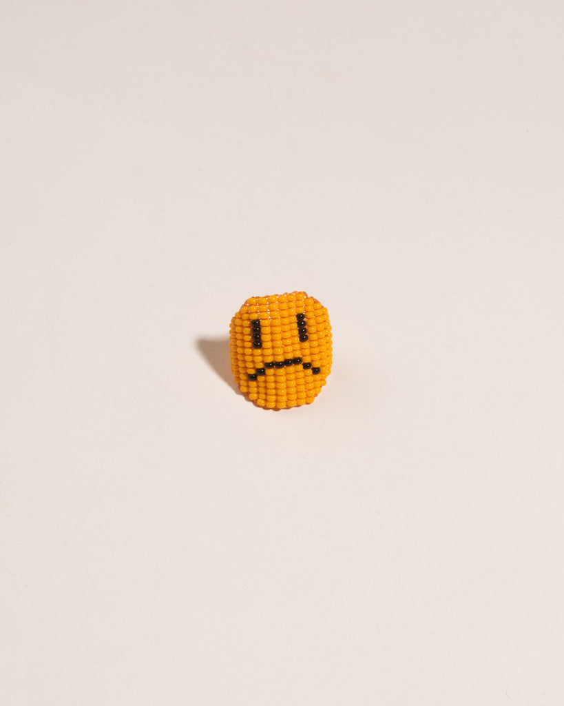 Beaded frowning face ring with orange background 