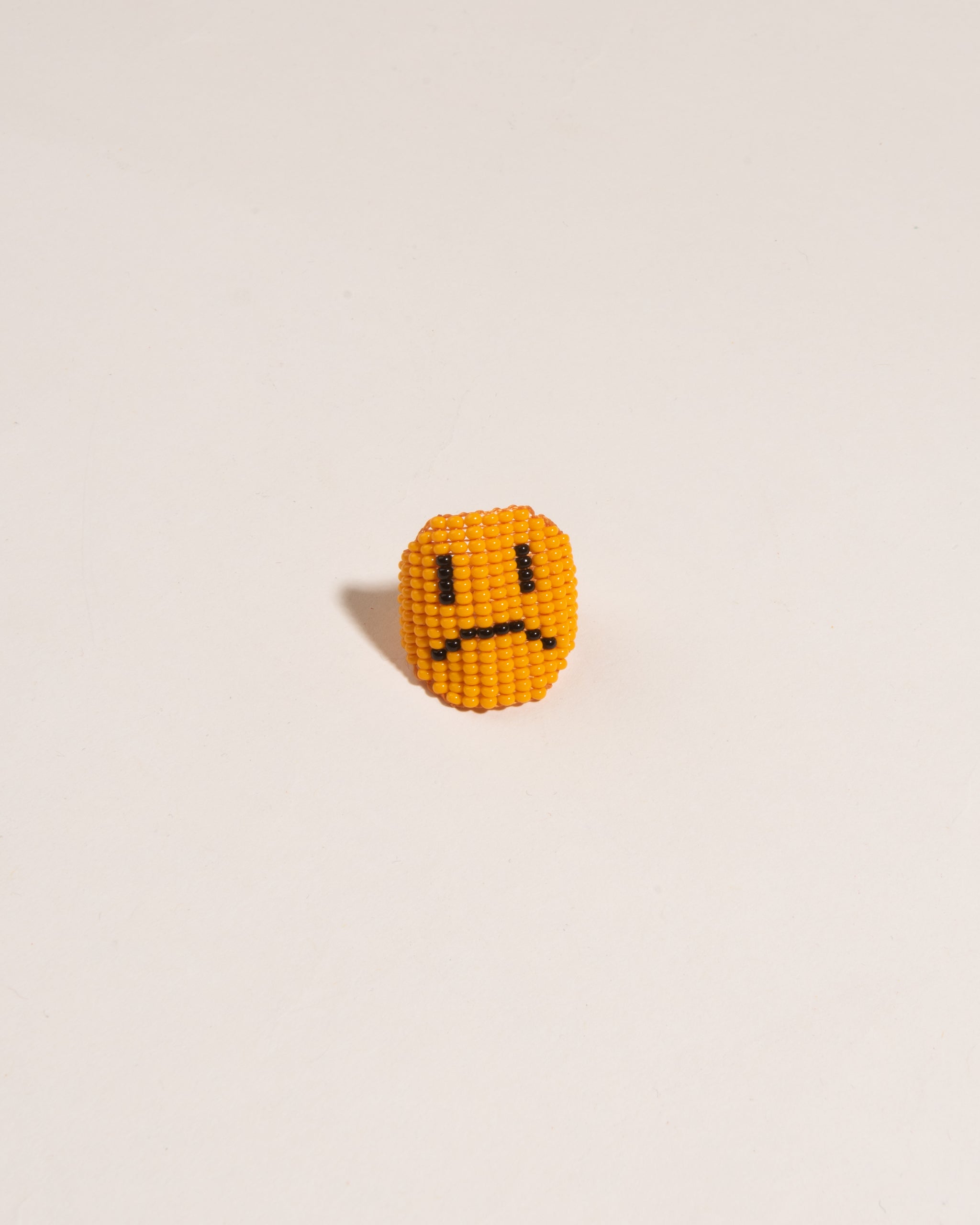 Beaded frowning face ring with orange background 